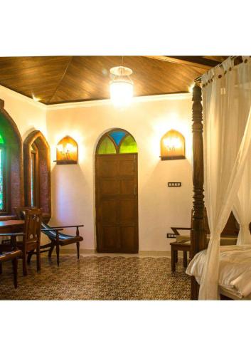 a room with a bed and tables and a wooden door at villa goa in Cola
