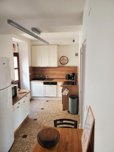 a kitchen with white cabinets and a wooden table at À la croisée des Louvières - Le Mesnil sur Oger in Le Mesnil-sur-Oger