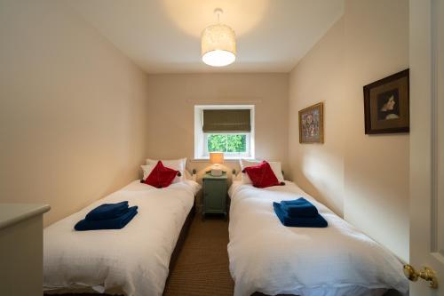 Duas camas num quarto com almofadas vermelhas e azuis em Riverside Cottage, Bridge of Balgie, Glenlyon, Perthshire 