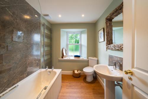 a bathroom with a tub and a toilet and a sink at Riverside Cottage, Bridge of Balgie, Glenlyon, Perthshire 