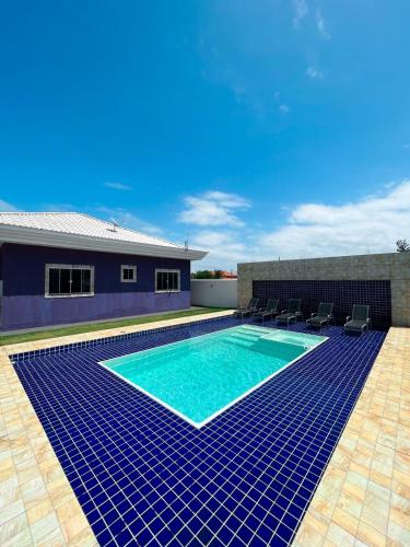 a swimming pool with blue tiles in front of a house at casa de praia com piscina e hidromassagem in Arraial do Cabo