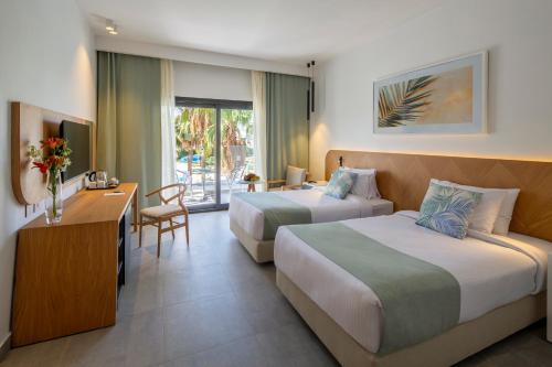 シャルム・エル・シェイクにあるAmphoras Beachのベッド2台とデスクが備わるホテルルームです。