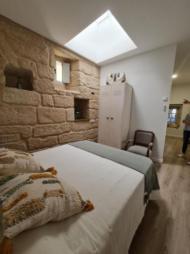 a bedroom with a large bed and a stone wall at Pensión A Xanela in Pontevedra