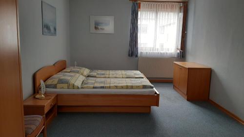 ein Schlafzimmer mit einem Bett, einer Kommode und einem Fenster in der Unterkunft Appartementhaus Lang in Mörbisch am See