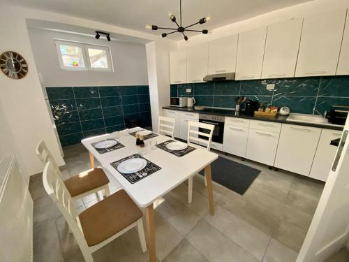 eine Küche mit einem weißen Tisch, einem Tisch und Stühlen in der Unterkunft Deluxe Apartment #CasaMihai Free Parking in Braşov