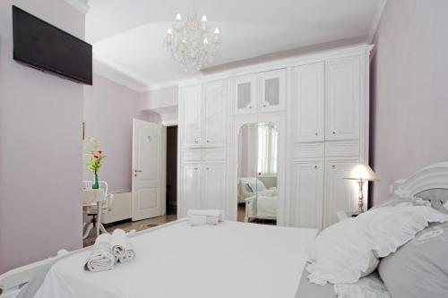 a white bedroom with a large bed and a chandelier at B&B Elisir in Albenga