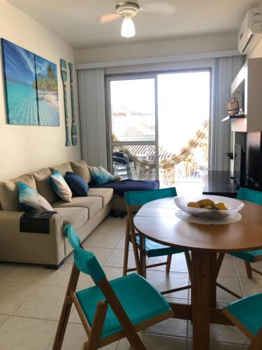 sala de estar con sofá, mesa y sillas en Apartamento peracanga com vista para o mar en Guarapari
