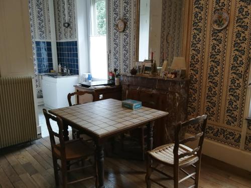 uma sala de jantar com mesa e cadeiras e uma cozinha em La Folia - Ferme de Lucqy 