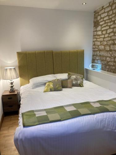 a bedroom with a large bed with a green headboard at Linnaea Rooms - Corston Nr Malmesbury in Malmesbury