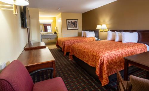 a hotel room with two beds and a table and chairs at Loyalty Inn Hawkinsville in Hawkinsville