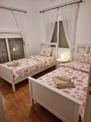 two beds in a room with two windows at Protaras sea view Villa with private pool in Protaras