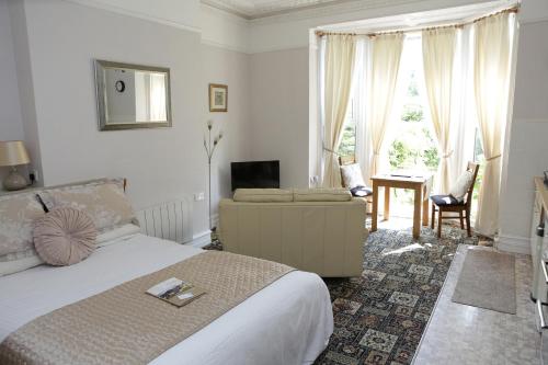 a bedroom with a bed and a couch and a television at Abbey View Holiday Flats in Torquay