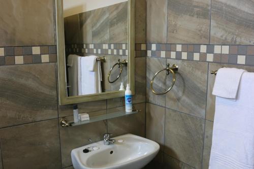 uma casa de banho com lavatório, espelho e toalhas em Livivane Guest House em Simunye