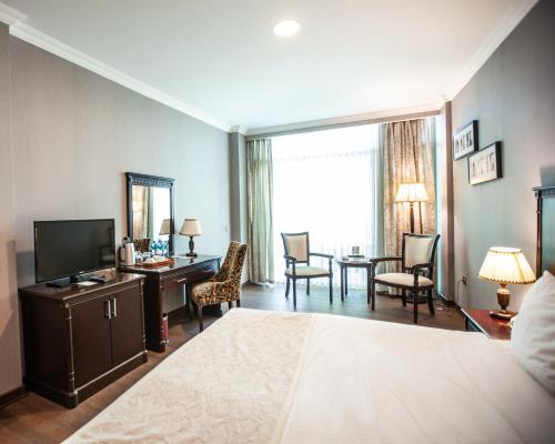 a hotel room with a bed and a desk and a television at Ramada by Wyndham Baku in Baku