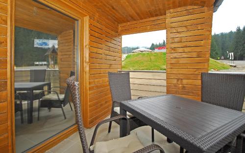 eine Terrasse mit einem Tisch, Stühlen und einem Fenster in der Unterkunft Apartment Bartek Ski Rental in Demänovská Dolina