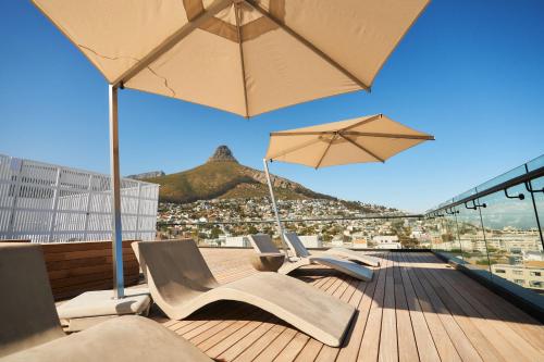 a deck with chairs and umbrellas on top of a building at Home Suite Hotels Station House in Cape Town