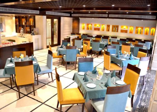 a dining room with blue tables and yellow chairs at The Central Park Hotel in Gwalior