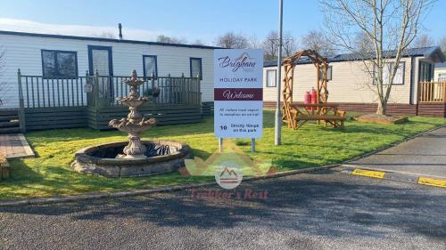 a sign in front of a park with a fountain at Trekker's Rest, Brigham, Cockermouth, Cumbria in Cockermouth