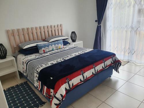 a bedroom with a bed with a red white and blue blanket at 29 Jeffs Place in Yzerfontein