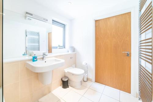 a bathroom with a toilet and a sink and a wooden door at Liverpool St Shoreditch London Terrace Apartment in London