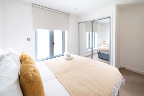 una camera da letto con un grande letto bianco con una grande finestra di Liverpool St Shoreditch London Terrace Apartment a Londra