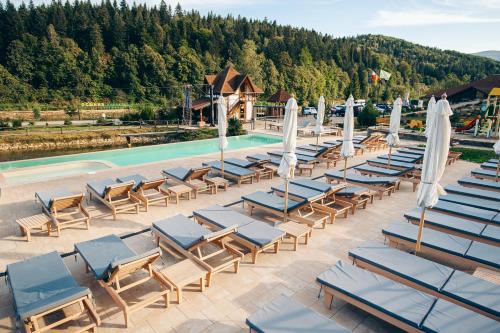a row of lounge chairs and umbrellas next to a swimming pool at Osonnya Karpaty RESORT MEDICAL & SPA in Skhidnitsa