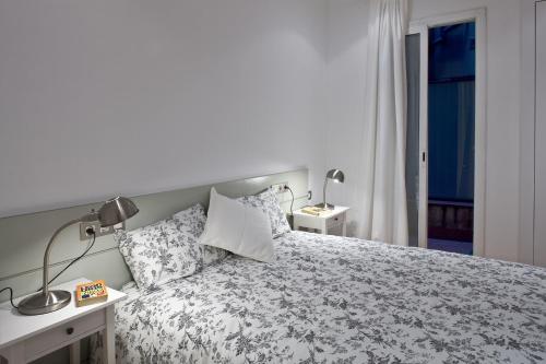バルセロナにあるFlateli Llúriaのベッドルーム1室(ベッド1台、ランプ2つ、窓付)