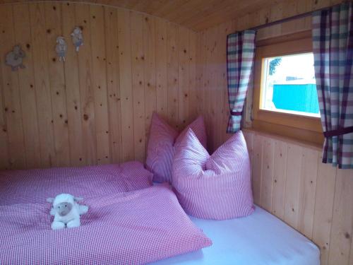 ein Schlafzimmer mit rosa Kissen und einem Teddybär auf dem Bett in der Unterkunft Hof Gruebler in Klipphausen