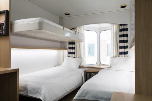 two beds in a small room with a window at Tallink Silja Line Ferry - Helsinki to Stockholm in Helsinki