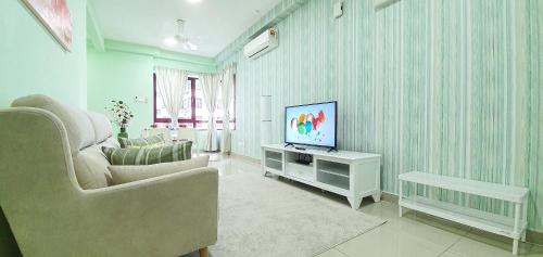 een woonkamer met een televisie en een bank bij Rafflesia Condominium by Dahlia Homes in Kuala Lumpur