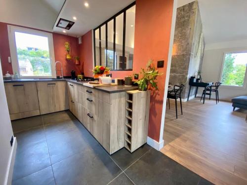 a large kitchen with wooden cabinets and orange walls at Proche centre ville, gîte 4 étoiles avec piscine in Dijon