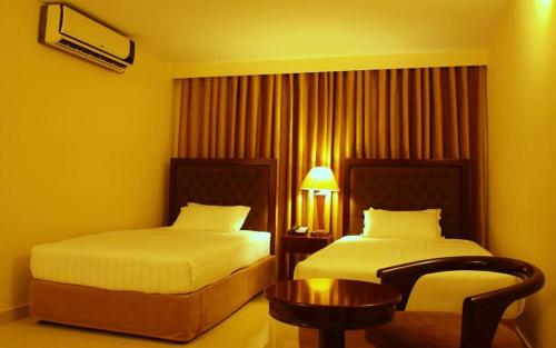 una habitación de hotel con dos camas y una silla en Hotel Aristos Boutique & Suites, en Chittagong