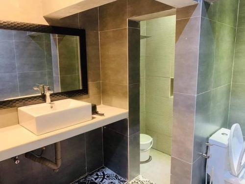 a bathroom with a sink and a mirror and a toilet at Palazzo 1 HotSpring,3Bedrooms 35to40pax, Pansol Calamba in Pansol