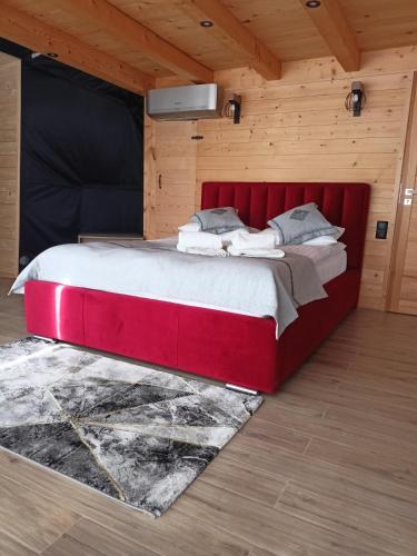 duże czerwone łóżko w pokoju z drewnianymi ścianami w obiekcie Luxury Glamp w mieście Bańska Niżna
