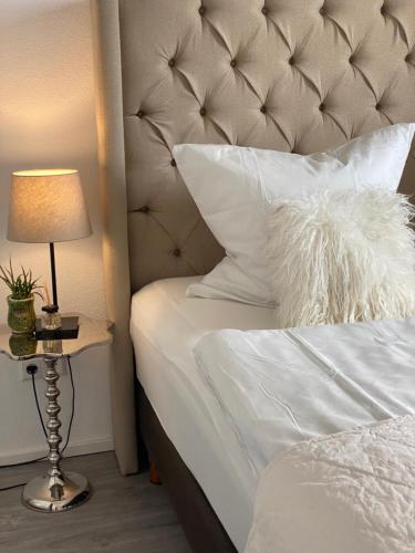 a bed with white sheets and a lamp on a table at Aurum Apartment in Kirchheim am Neckar