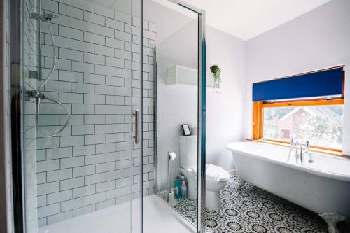 La salle de bains est pourvue d'une baignoire et d'une douche en verre. dans l'établissement Gorgeous Victorian house sleeps 6 in Cardiff, à Cardiff