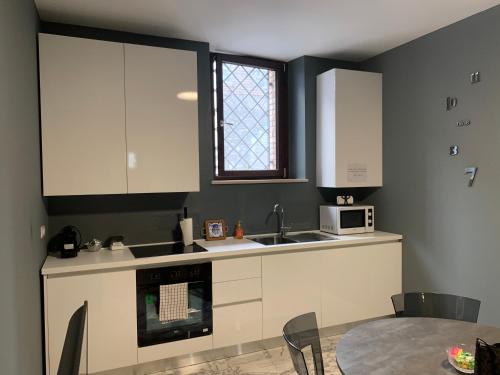 kuchnia z białymi szafkami, zlewem i stołem w obiekcie Modern city center apartment w mieście Benewent