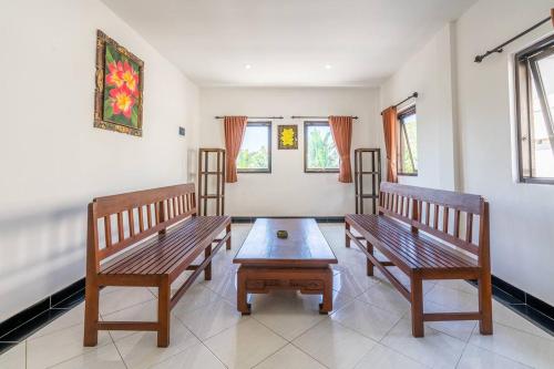 two wooden benches in a room with a table at Ganandra Stay Denpasar in Denpasar