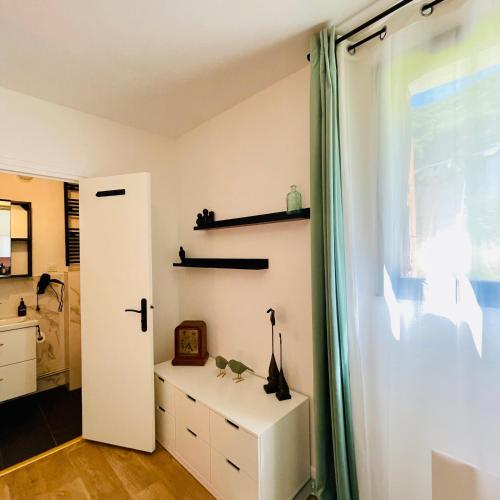 Zimmer mit einer Tür, einem Fenster und einer Kommode in der Unterkunft L'Ekrin des Cimes in Le Mont-Dore