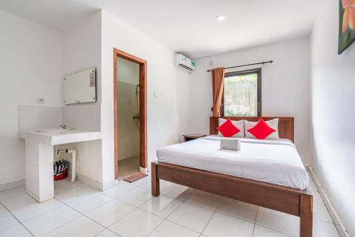a bedroom with a bed and a sink and a mirror at Ganandra Stay Denpasar in Denpasar