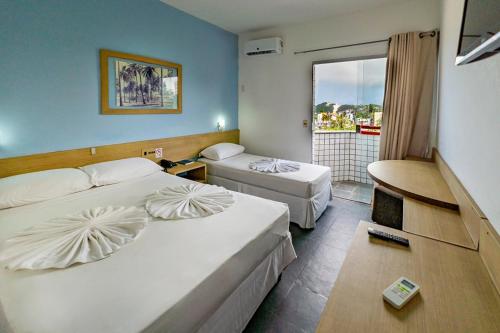 a hotel room with two beds and a balcony at Happy Ponta Negra Express in Natal