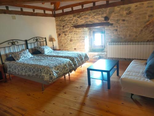 a bedroom with two beds and a couch and a table at Don Baldomero Hotel Rural in Cadiñanos