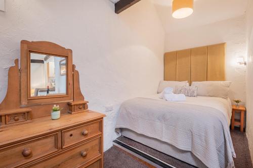 ein Schlafzimmer mit einem Bett, einem Spiegel und einer Kommode in der Unterkunft Cottage 6 Studio Mews in Keswick