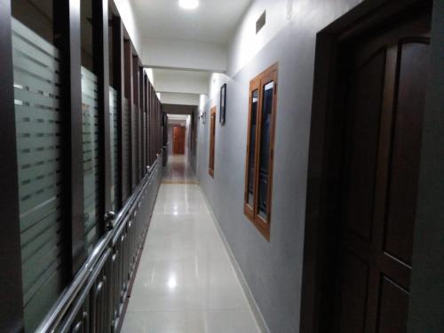 a hallway of a building with white walls and wooden doors at MP RESIDANCY in Perintalmanna