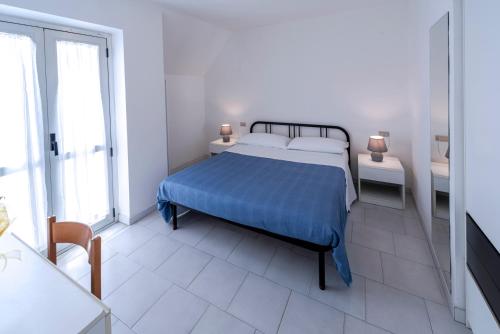 a white bedroom with a bed with a blue blanket at Residence Dolcemare in San Benedetto del Tronto