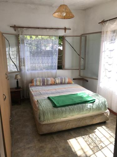 a bedroom with a bed with a green blanket on it at Marindia, hermosa casa, Ideal descanso, Montemar. in Salinas 