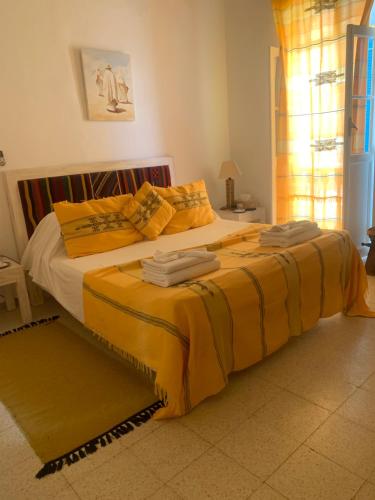 a bedroom with a large bed with yellow sheets at Dar Lola Djerba in Houmt Souk