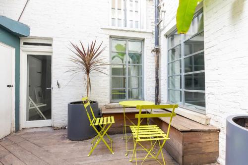 a yellow table and chairs on a patio at Stylish 2 Bedroom Converted Victorian Storefront in London