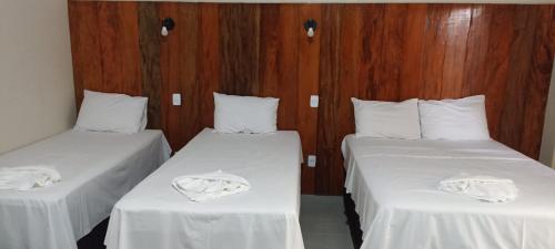 a room with two beds with white sheets and wooden walls at EL SHADDAY HOTEL in Diamante do Norte