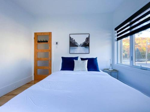 - une chambre avec un grand lit blanc et des oreillers bleus dans l'établissement Complexe LIVTremblant by Gestion ELITE - LIV4, à Mont-Tremblant
